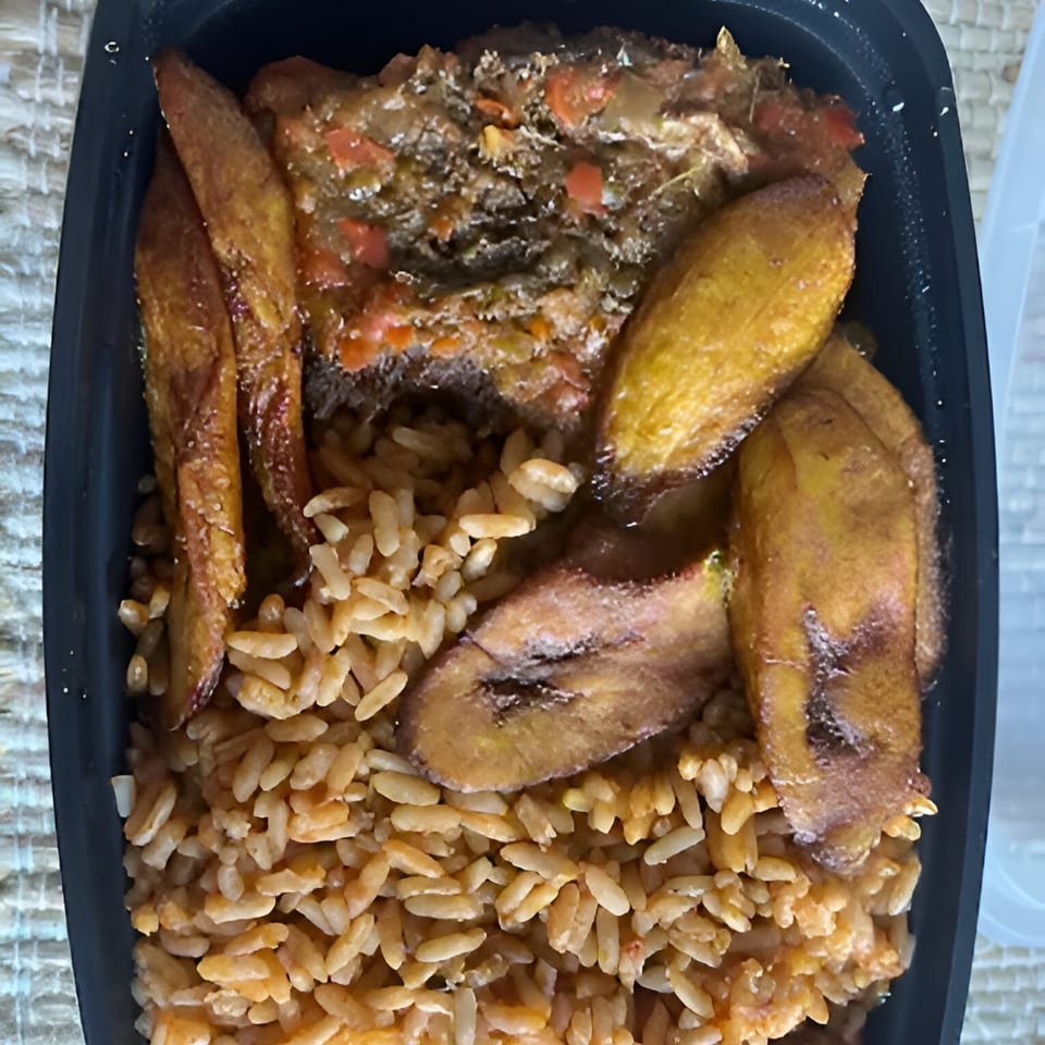 African cuisine meal with jollof rice, fried plantains, and a rich stew in a black container.